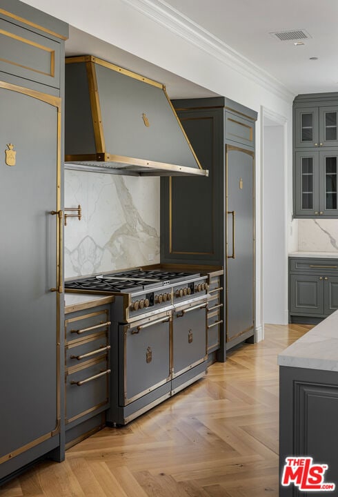 kitchen featuring gray cabinetry, wall chimney range hood, light parquet floors, and premium appliances