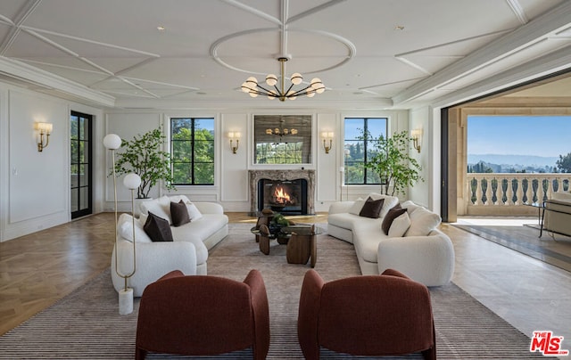 living room featuring a healthy amount of sunlight, coffered ceiling, a chandelier, and a mountain view