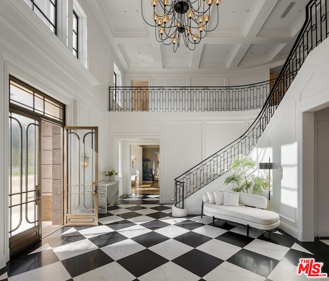 entrance foyer with coffered ceiling, ornamental molding, and a high ceiling