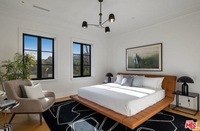 bedroom featuring crown molding, light hardwood / wood-style floors, and a chandelier