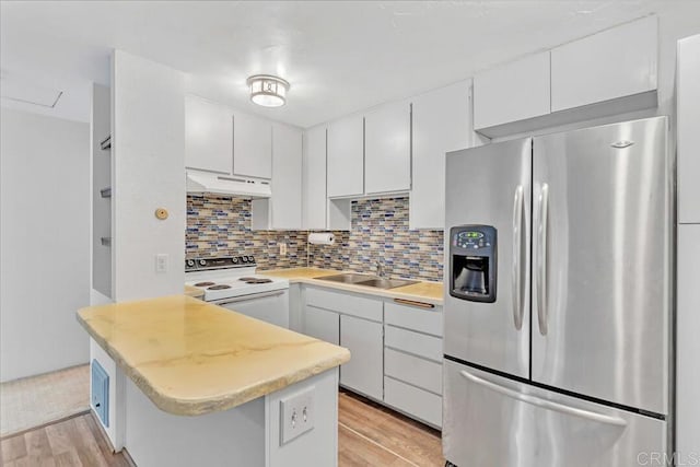 kitchen featuring tasteful backsplash, white cabinetry, white electric range oven, and stainless steel fridge