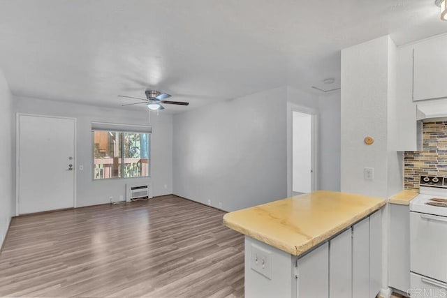 kitchen with white cabinetry, backsplash, white electric range oven, heating unit, and kitchen peninsula