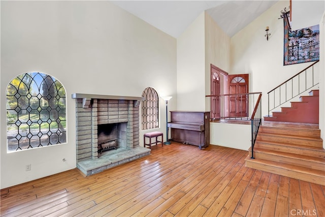 unfurnished living room featuring a fireplace, high vaulted ceiling, and light wood-type flooring