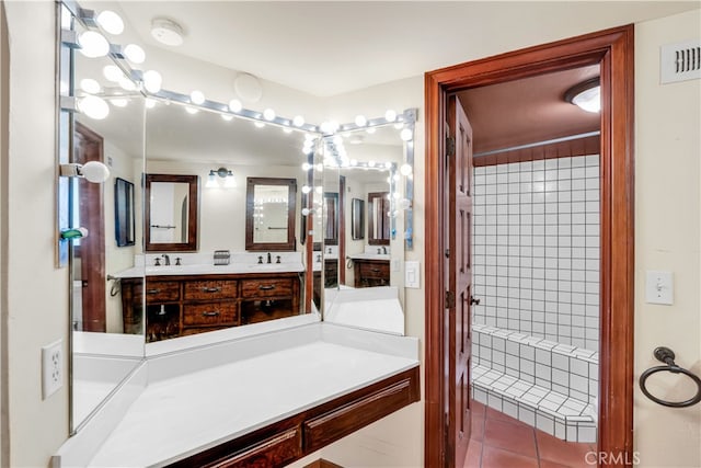 bathroom featuring tile patterned floors, vanity, and a tile shower