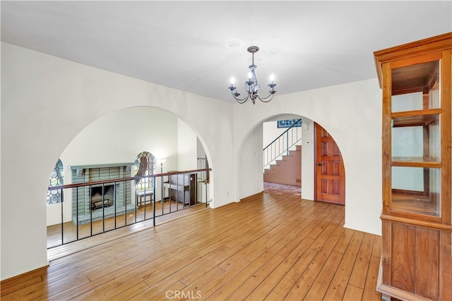 living room featuring a brick fireplace, an inviting chandelier, and light hardwood / wood-style floors