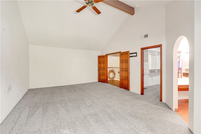 unfurnished bedroom with ceiling fan, beam ceiling, high vaulted ceiling, light carpet, and a spacious closet