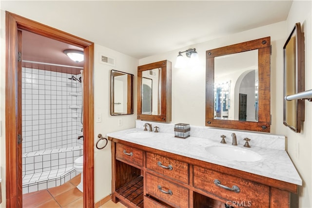 bathroom featuring tile patterned flooring, vanity, tiled shower, and toilet