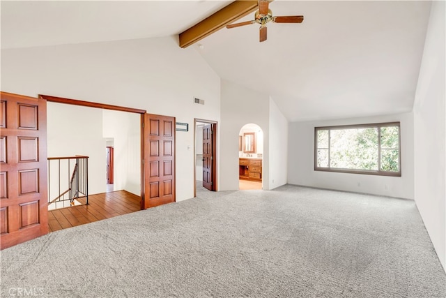 unfurnished bedroom featuring connected bathroom, high vaulted ceiling, beamed ceiling, carpet floors, and ceiling fan