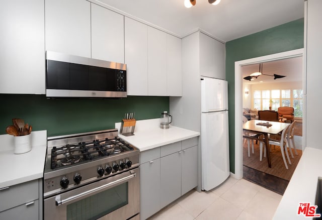 kitchen featuring ceiling fan, light tile patterned flooring, white cabinetry, and stainless steel appliances