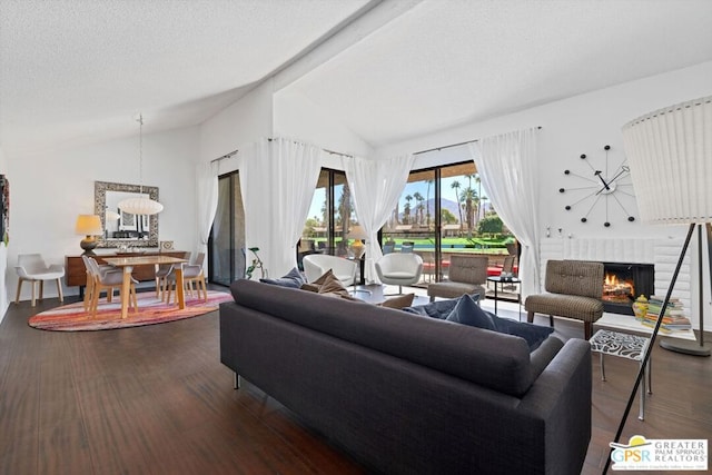 living room with a fireplace, a textured ceiling, dark wood-type flooring, and lofted ceiling