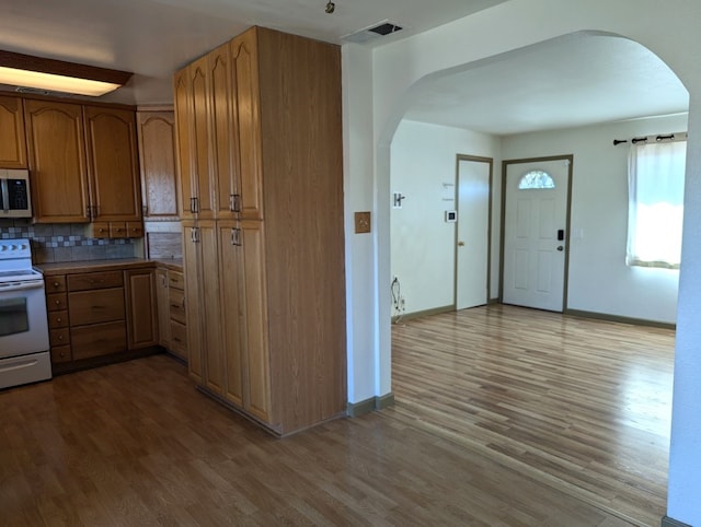 kitchen featuring white electric range oven, light hardwood / wood-style flooring, and tasteful backsplash