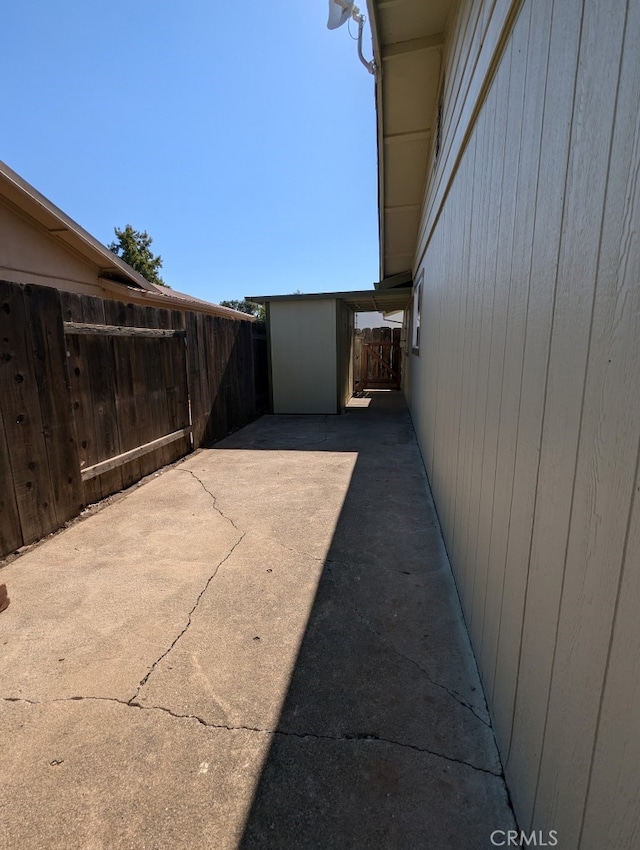 view of side of home featuring a storage shed and a patio