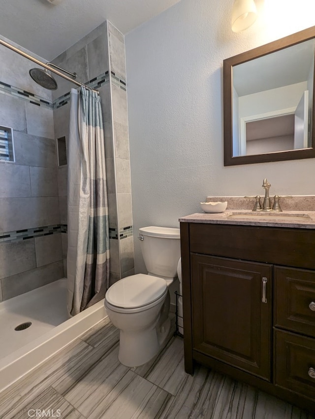 bathroom featuring toilet, walk in shower, and vanity