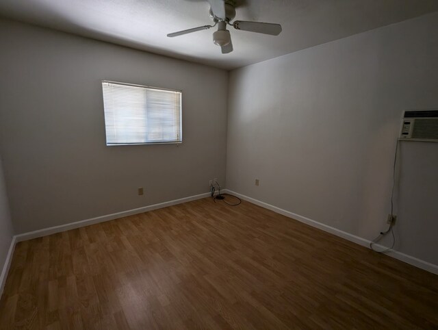 spare room with dark hardwood / wood-style floors, a wall mounted AC, and ceiling fan