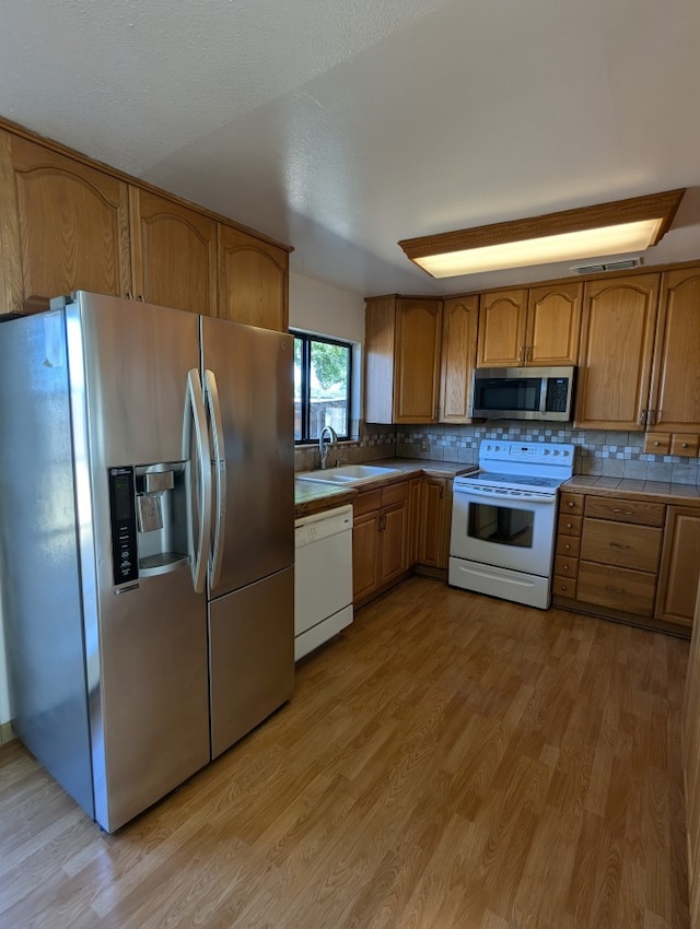 kitchen with tile countertops, sink, light hardwood / wood-style flooring, and stainless steel appliances