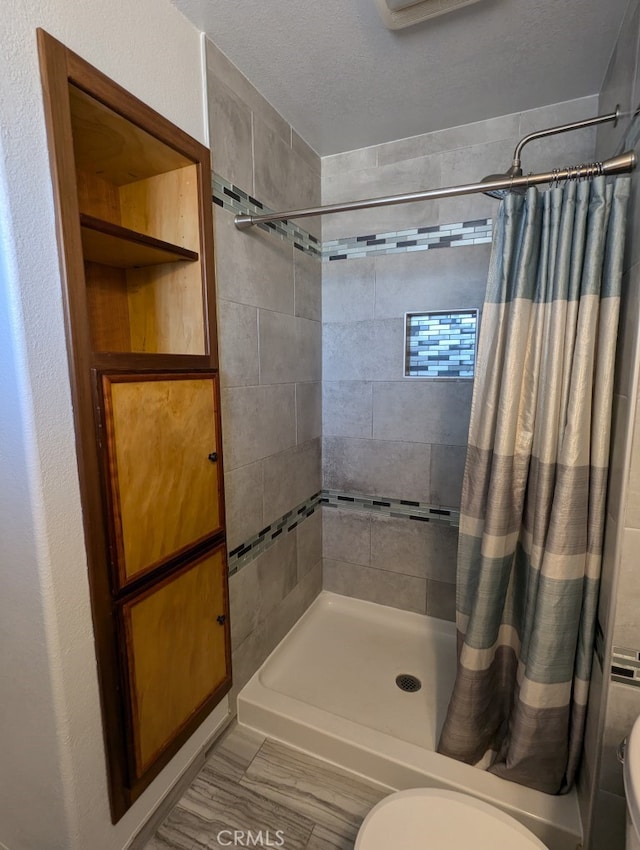 bathroom with curtained shower, a textured ceiling, and toilet