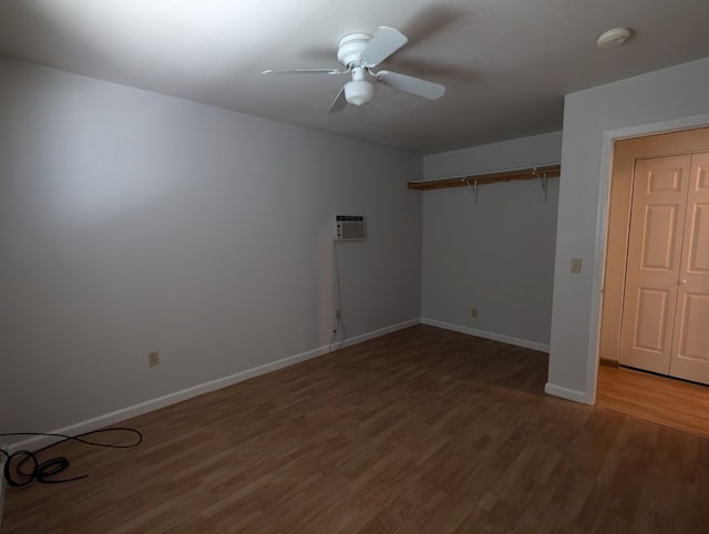 empty room with a wall unit AC, ceiling fan, and dark hardwood / wood-style flooring