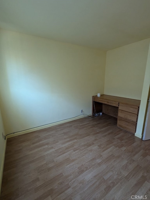 spare room with built in desk and light hardwood / wood-style floors