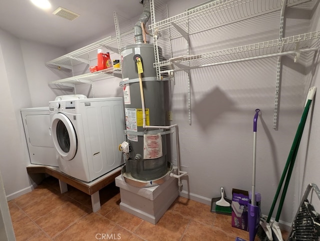 washroom with water heater, separate washer and dryer, and tile patterned flooring