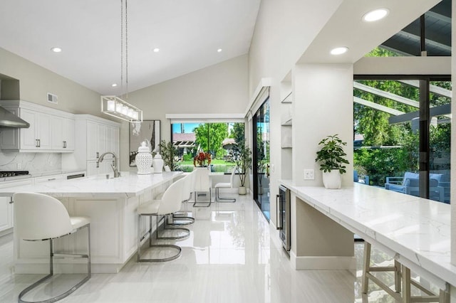 kitchen with white cabinetry, decorative light fixtures, plenty of natural light, and a breakfast bar area