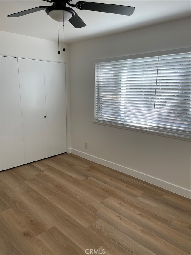 unfurnished bedroom featuring hardwood / wood-style flooring, a closet, and ceiling fan