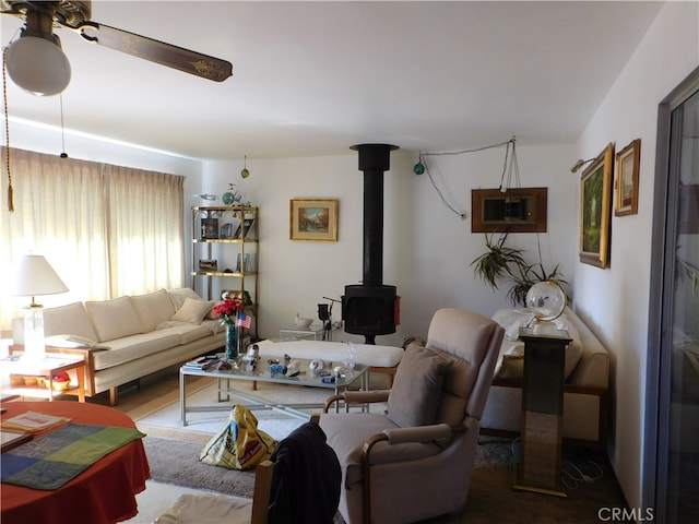 carpeted living room featuring a wood stove and ceiling fan