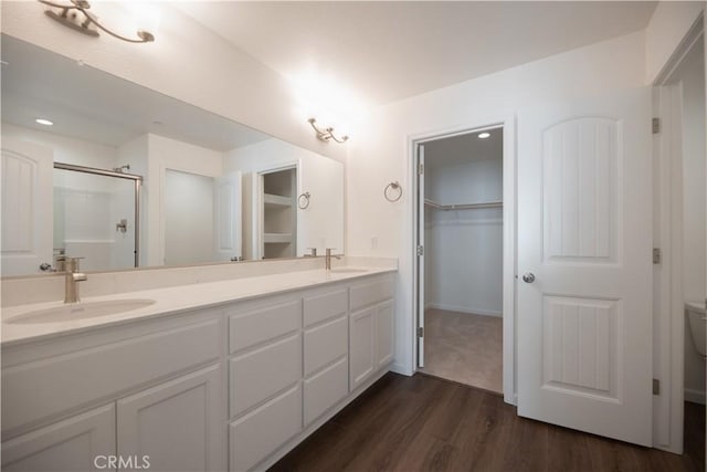 bathroom featuring a shower with door, vanity, wood-type flooring, and toilet