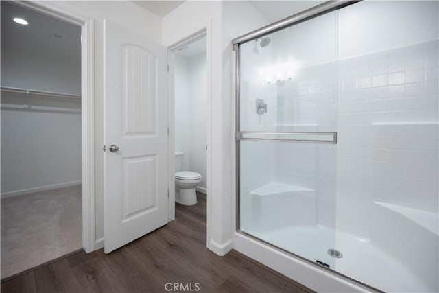 bathroom with hardwood / wood-style flooring, toilet, and walk in shower