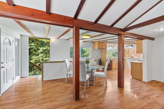 dining room featuring lofted ceiling with beams and light hardwood / wood-style floors