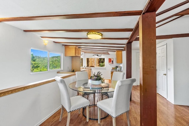 dining space with light hardwood / wood-style floors and lofted ceiling with beams