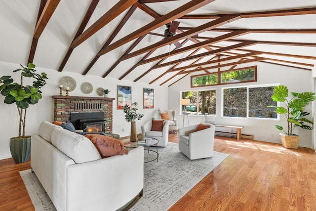 living room featuring vaulted ceiling with beams, a baseboard heating unit, ceiling fan, a brick fireplace, and light wood-type flooring