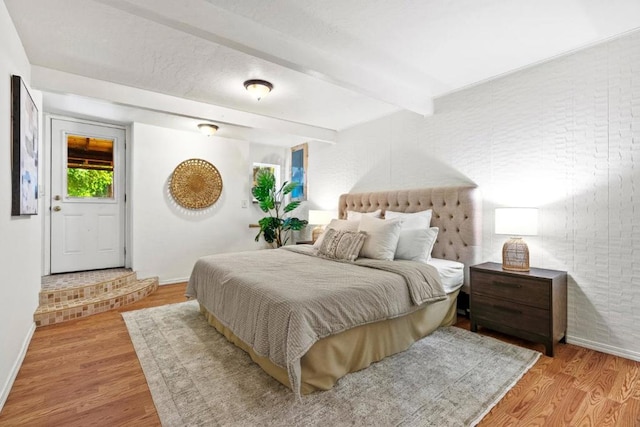 bedroom featuring beam ceiling and light hardwood / wood-style floors