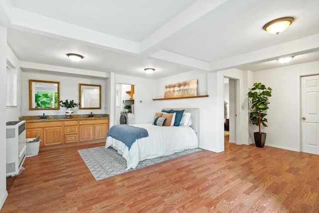 bedroom featuring beamed ceiling, washer / dryer, sink, and light wood-type flooring