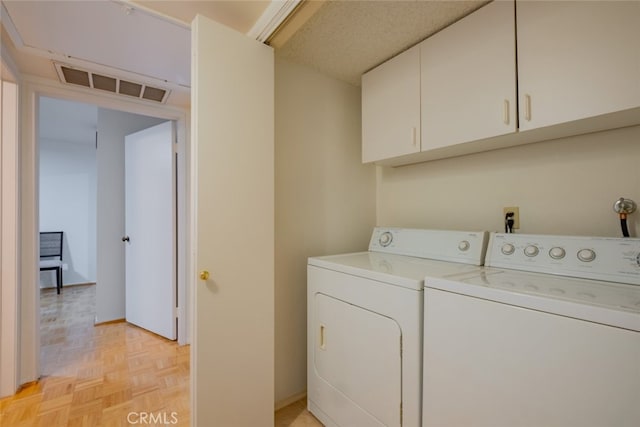 laundry room featuring washer and clothes dryer, cabinets, and light parquet flooring