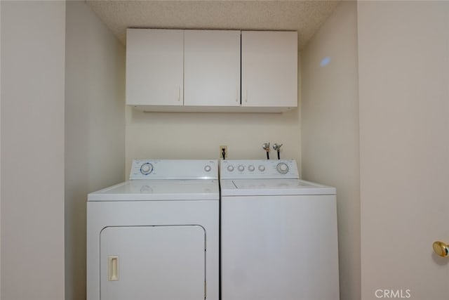 clothes washing area featuring cabinets, a textured ceiling, and washing machine and dryer