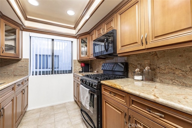 kitchen featuring black appliances, tasteful backsplash, ornamental molding, light stone counters, and a tray ceiling