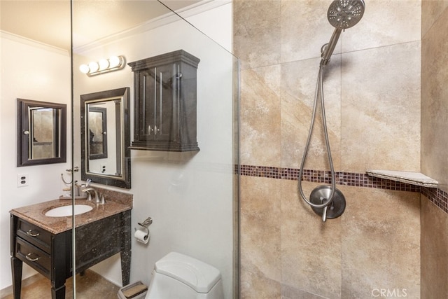 bathroom with tiled shower, vanity, crown molding, and toilet