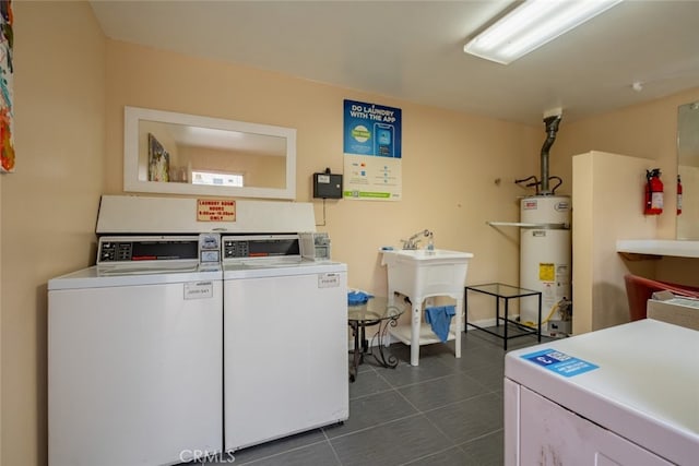 laundry room featuring sink, gas water heater, dark tile patterned floors, and separate washer and dryer