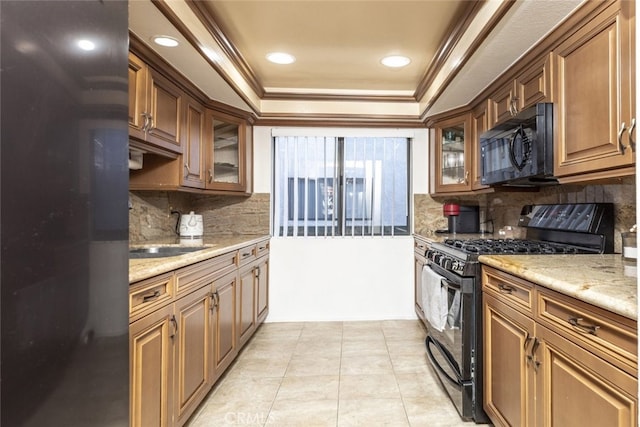 kitchen featuring black appliances, tasteful backsplash, ornamental molding, light stone counters, and a tray ceiling