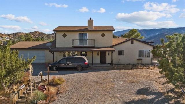 back of house featuring a mountain view, a balcony, and a garage