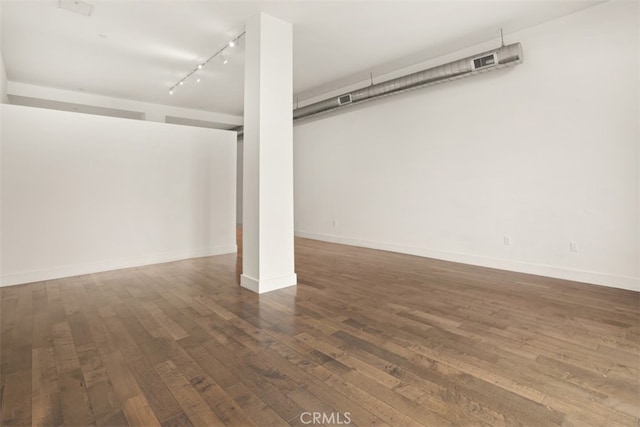 basement featuring dark hardwood / wood-style floors and rail lighting