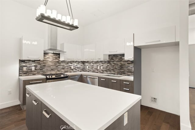 kitchen with white cabinets, wall chimney exhaust hood, sink, and hanging light fixtures