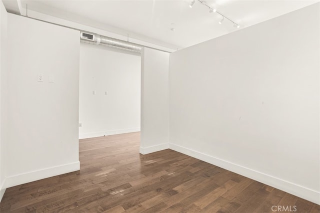 unfurnished room with track lighting and dark hardwood / wood-style floors