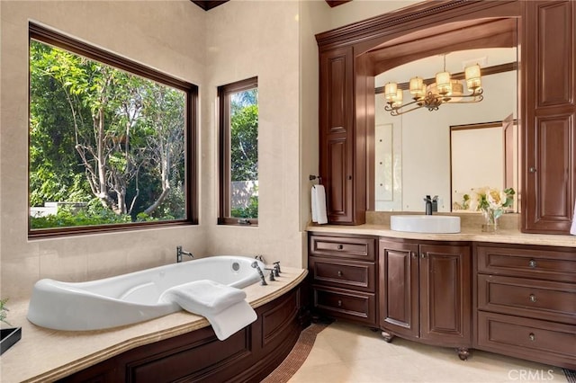 bathroom with tile patterned floors, vanity, a bath, and an inviting chandelier