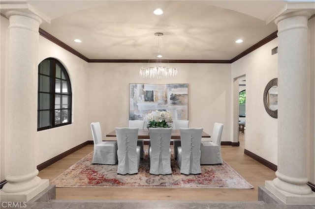 dining area with light wood-type flooring, crown molding, and a notable chandelier