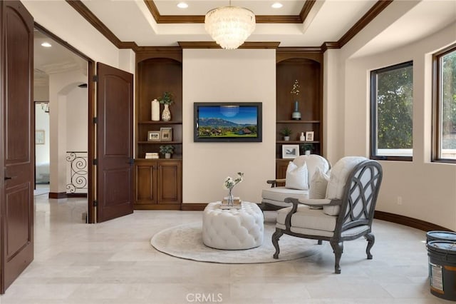 living area with built in shelves, a raised ceiling, ornamental molding, and an inviting chandelier