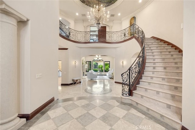 foyer with a towering ceiling, crown molding, and a notable chandelier