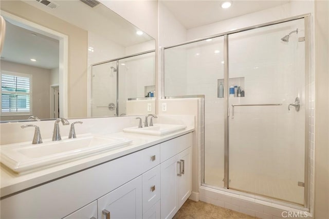 bathroom featuring double vanity, a stall shower, visible vents, and a sink