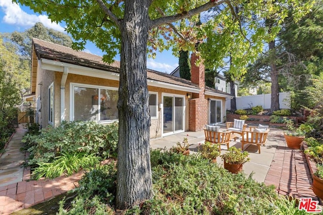 rear view of property featuring an outdoor living space and a patio area