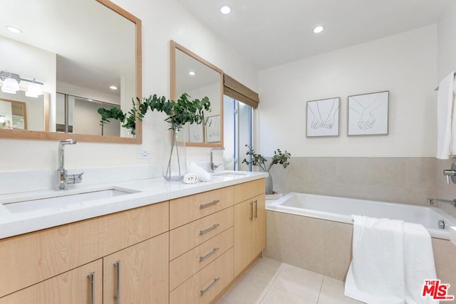 bathroom featuring tiled tub, tile patterned flooring, and vanity